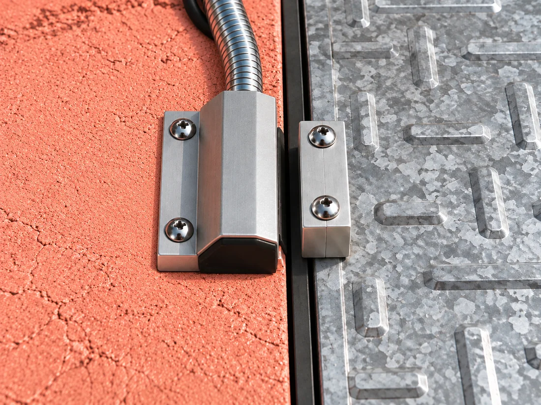 Wired magnetic contact on fixed pink concrete, with separate magnet on removable galvanized access cover